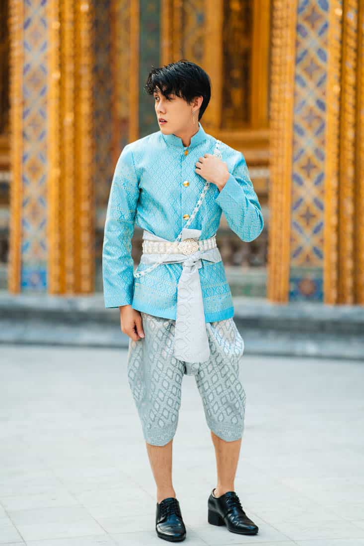 man dressed in thai costume standing in the temple
